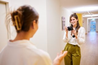 Een communicatiemedewerker met fotocamera die een collega fotografeert